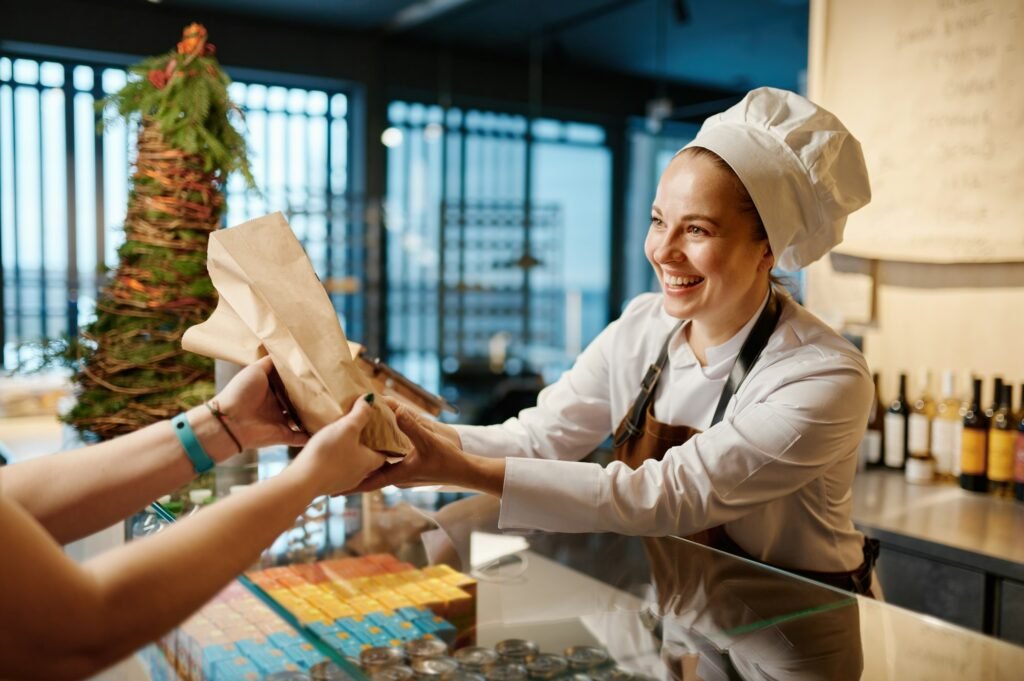 Bakery worker selling fresh tasty pastry and bread in bakery shop